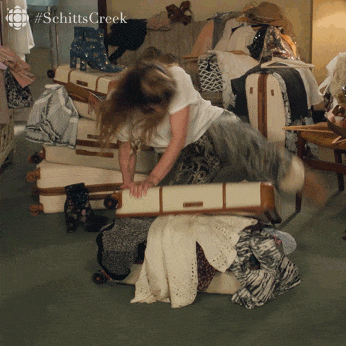 Alexis Rose from Schitt's Creek attempting to close her suitcase to close it. GIF is a joke about having to pack to relocate to the Netherlands.